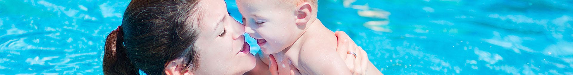 Eine junge Mutter verbringt die Zeit mit Ihrem Baby beim Babyschwimmkurs im Wellenspiel